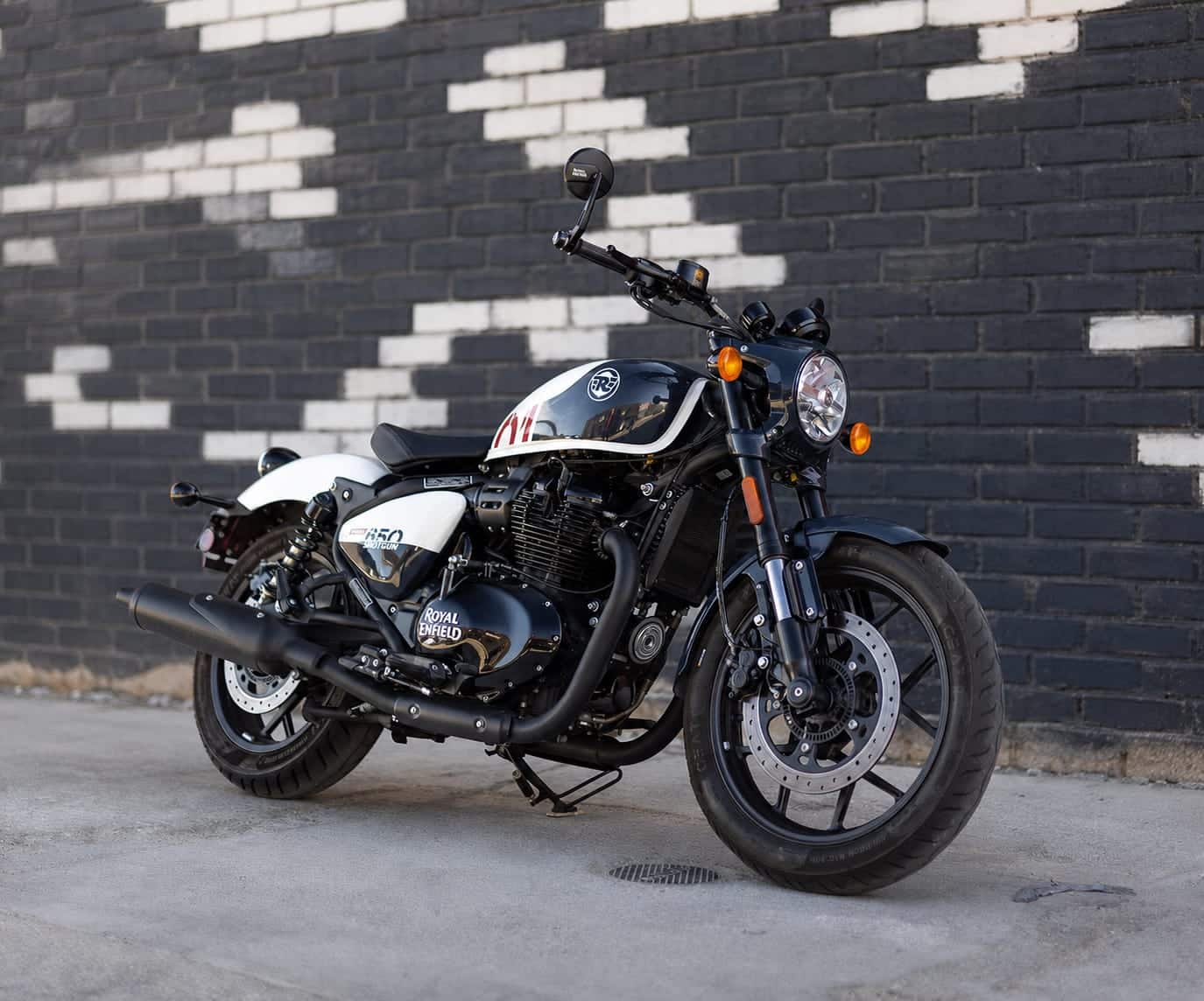 Royal Enfield Shotgun 650 Stencil White in front of a black and white brick wall